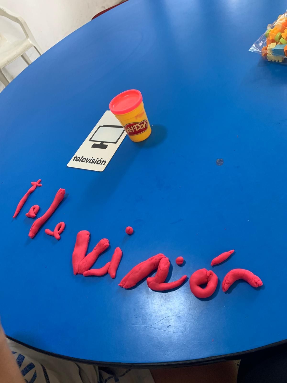 Mesa azul con letras rojas de Play-Doh que forman la palabra