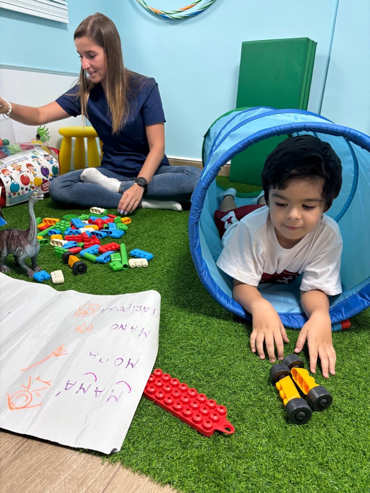 Una mujer está sentada en el suelo jugando con un niño en un túnel.