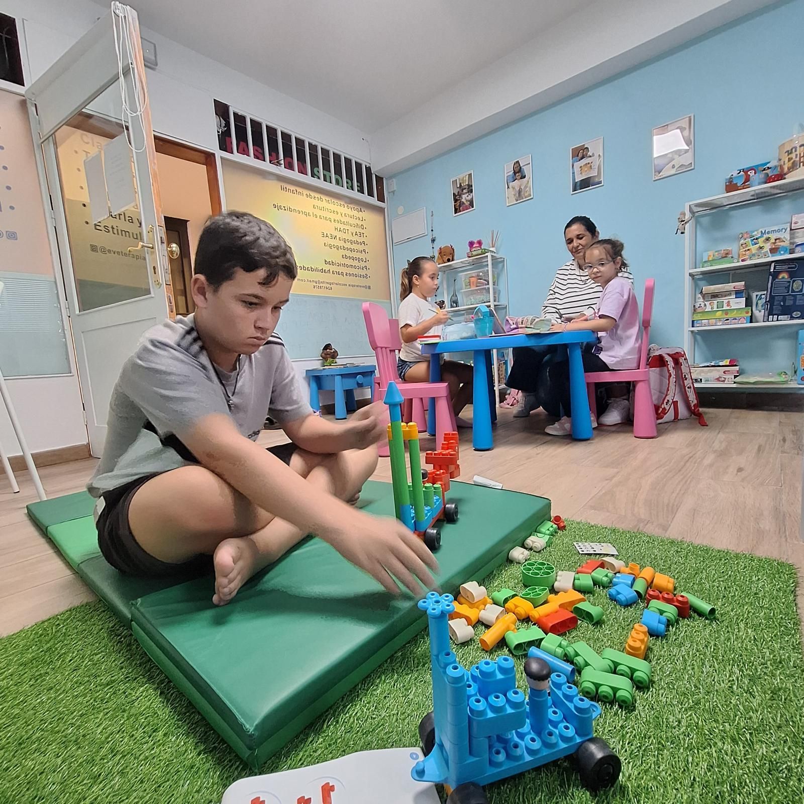 Un niño está sentado en el suelo jugando con bloques de Lego.