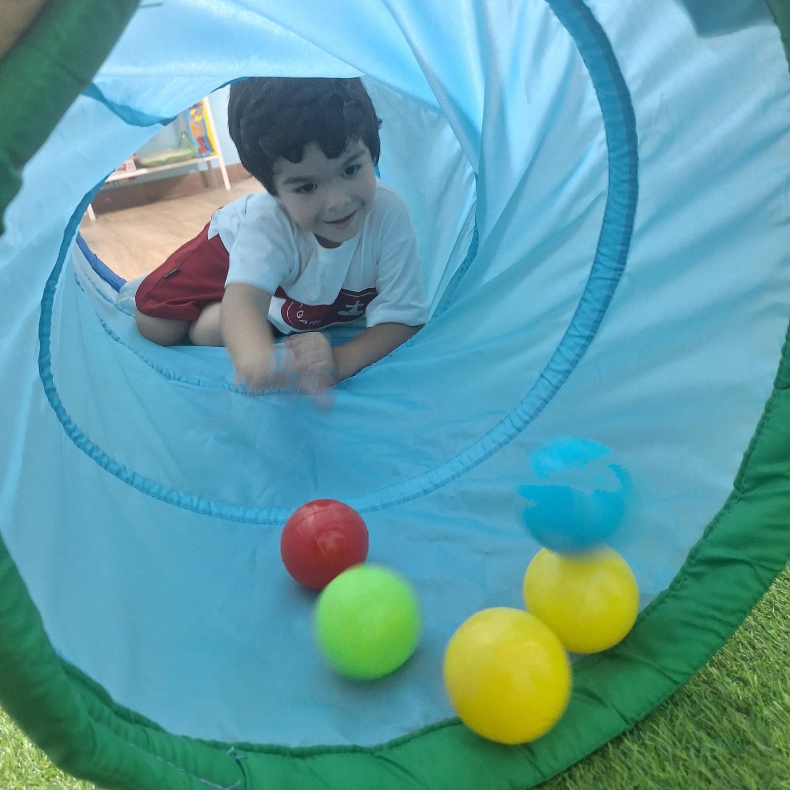 Un niño pequeño está jugando con pelotas en un túnel.