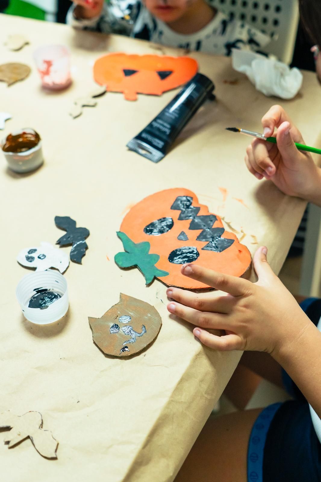 Un niño está pintando una calabaza con un pincel sobre una mesa.