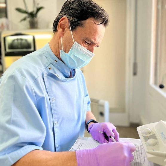 Un hombre que lleva una máscara y guantes morados está escribiendo en un trozo de papel.
