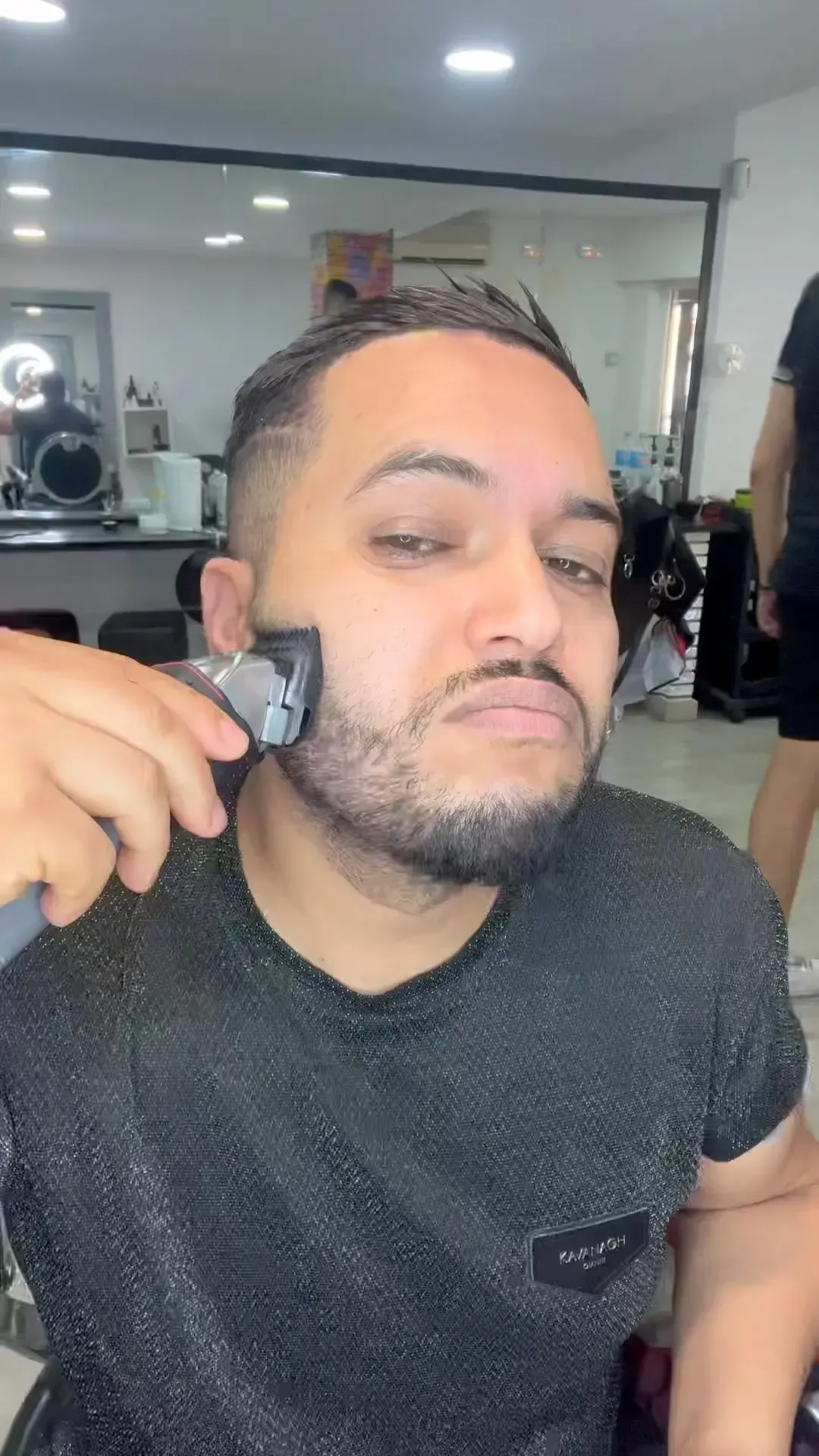 Hombre usando una máquina cortadora de pelo para recortarse la barba en un salón.