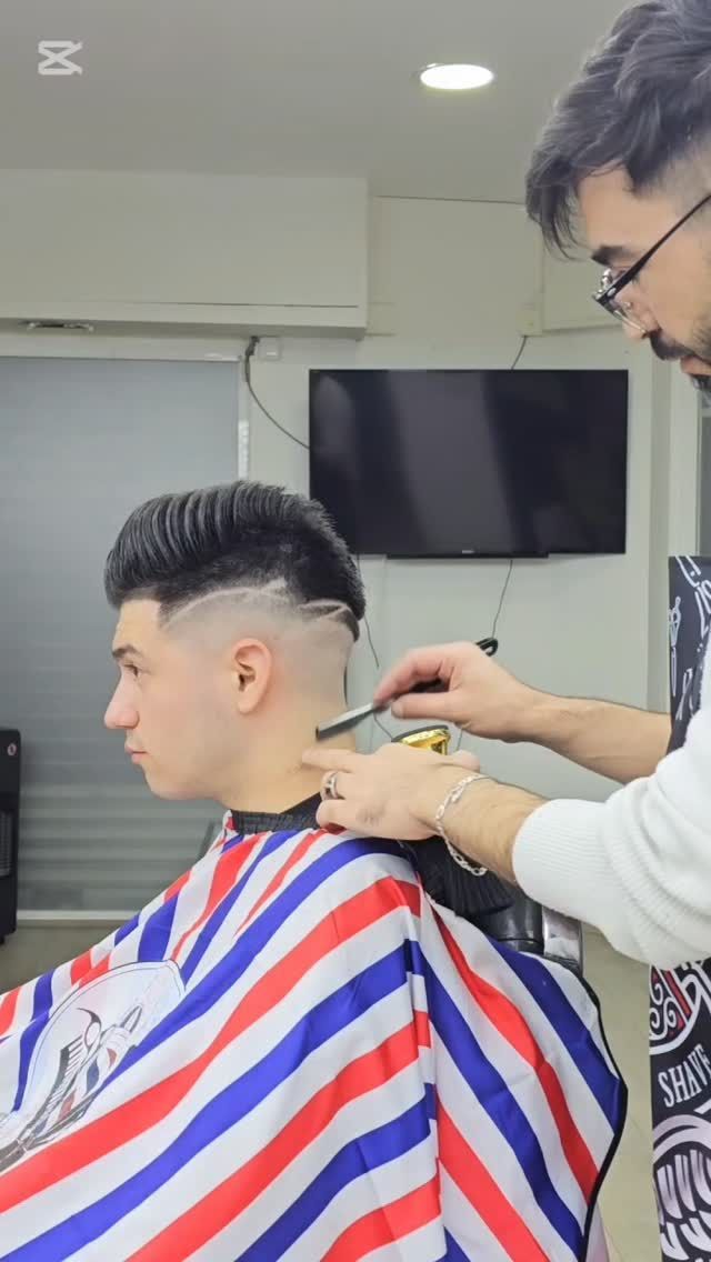 Un barbero recorta el cuello de un cliente con una maquinilla en una barbería.