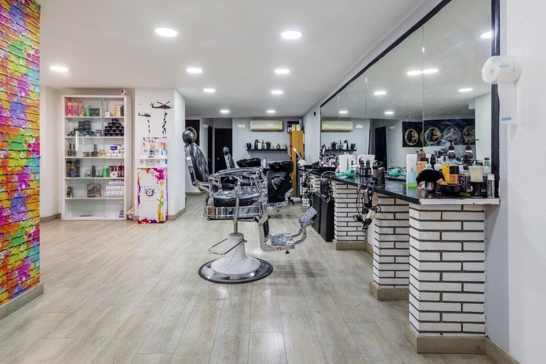 Interior de salón con sillas de barbero, espejos y exhibiciones de productos.