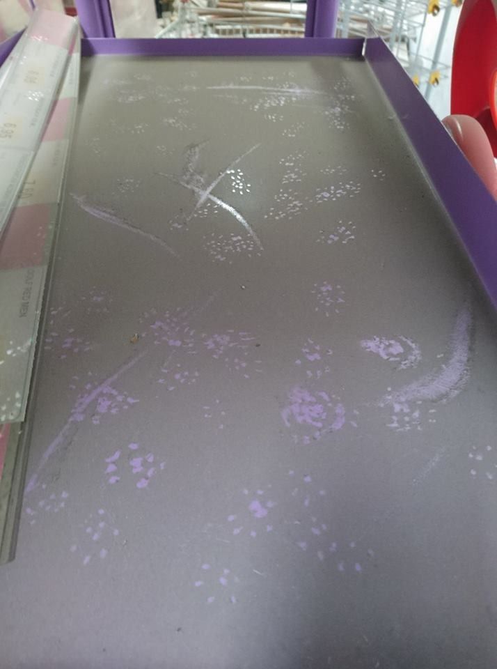 Una superficie rectangular con borde morado, con patrones dispersos de huellas de patas de color violeta claro y tenues marcas de arañazos blancos.