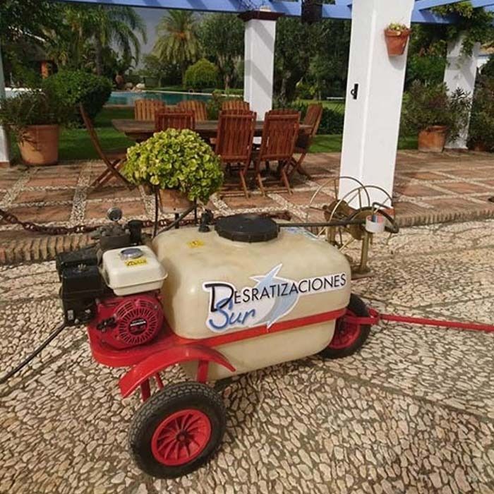 Un rociador de control de plagas con un motor rojo y un tanque etiquetado 