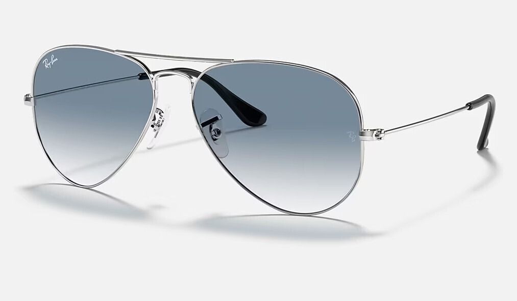 Un par de gafas de sol de aviador Ray-Ban con lentes azules sobre fondo blanco.