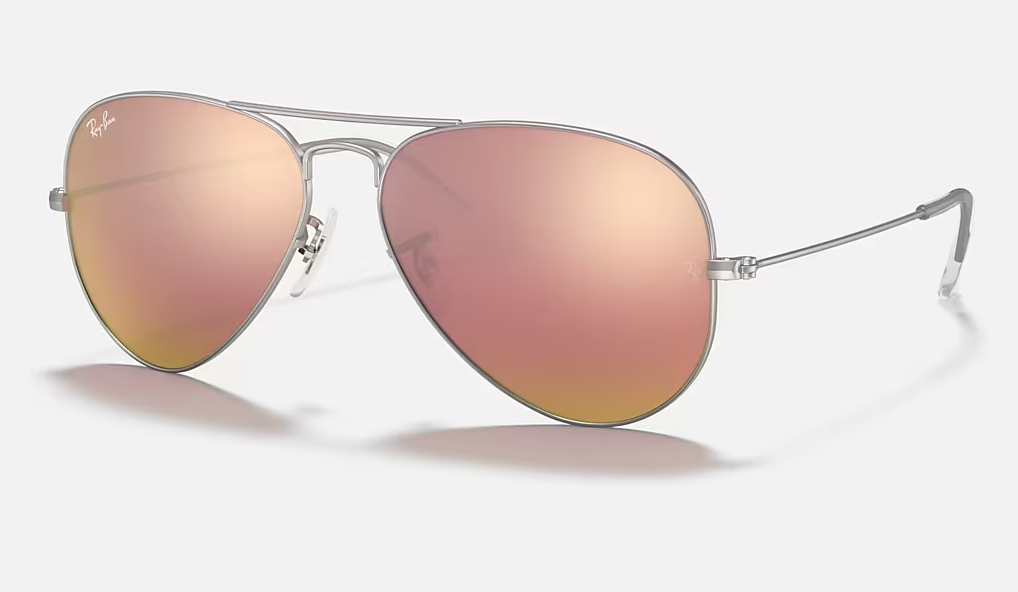 Un par de gafas de sol de aviador Ray-Ban con lentes rosas sobre fondo blanco.