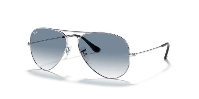 Un par de gafas de sol Ray-Ban están sobre una superficie blanca.