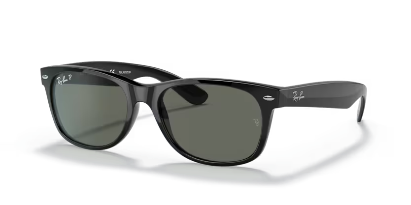 Un par de gafas de sol Ray-Ban negras están sobre una superficie blanca.