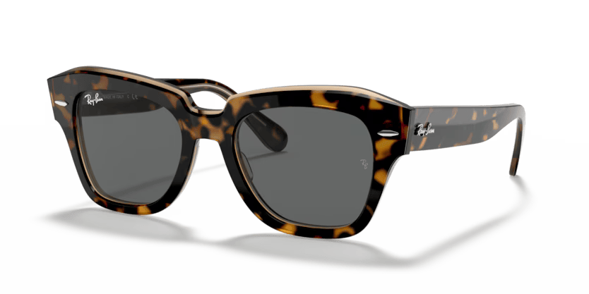 Un par de gafas de sol Ray-Ban cuadradas con lentes verdes sobre fondo blanco.