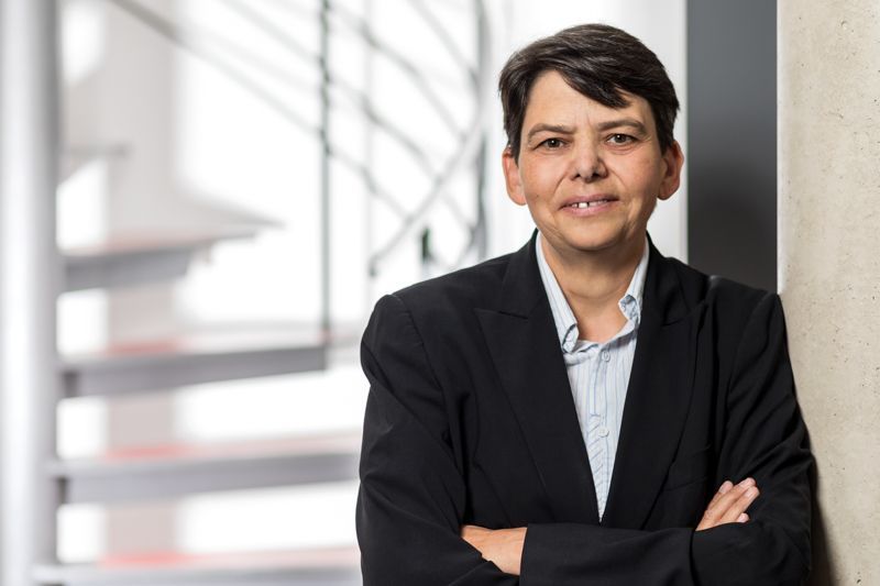 Eine Frau, die mit verschränkten Armen an einer Wand lehnt