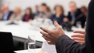 Ein Mann hält vor einer Gruppe von Leuten eine Rede.