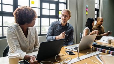 Eine Gruppe von Leuten sitzt mit Laptops an einem Tisch.