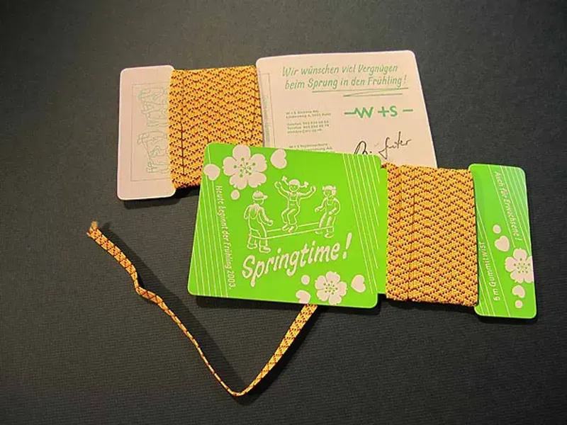 Verschiedene florale Geschenkkarten und eine grüne „Frühlingszeit!“-Karte mit einem geflochtenen Goldband auf dunklem Untergrund