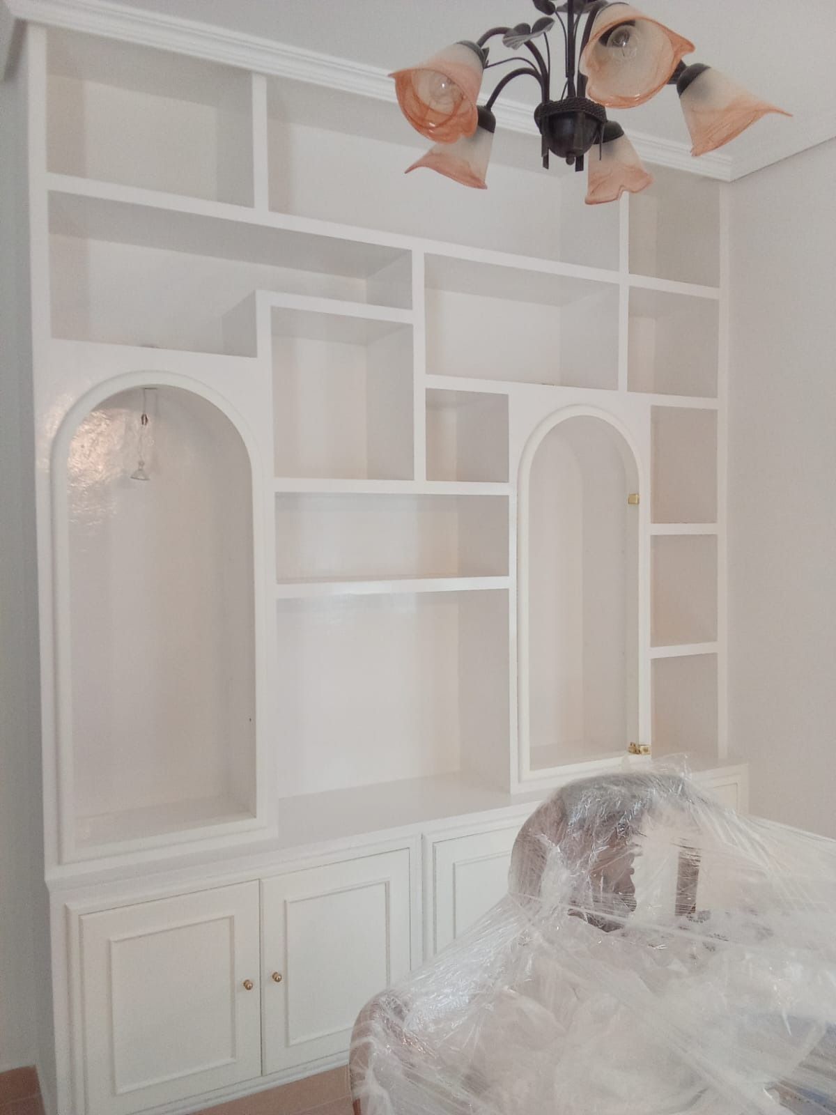 Estantería blanca empotrada con compartimentos de varios tamaños,