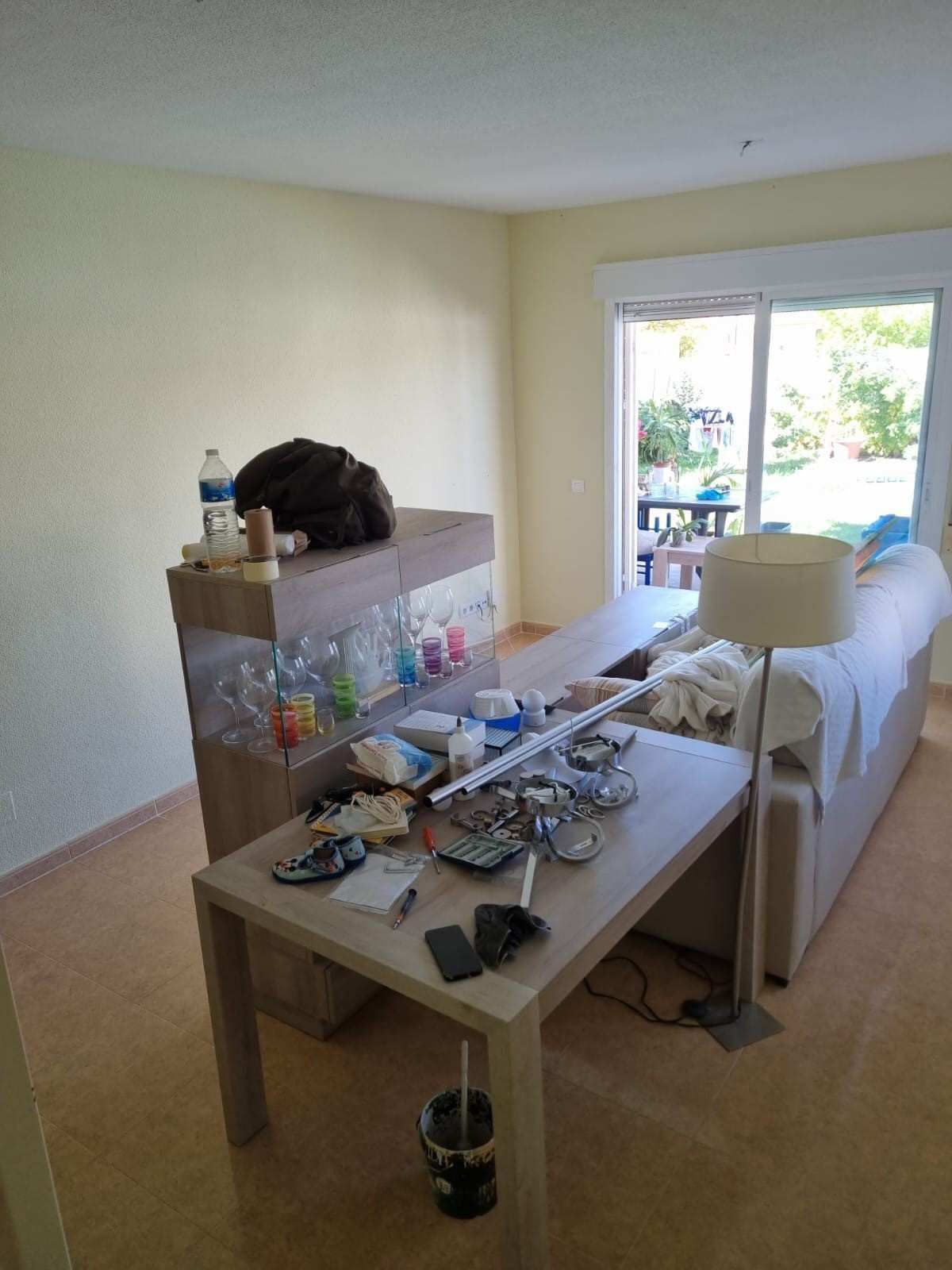 Una sala de estar desordenada con una mesa, un acuario, un sofá 