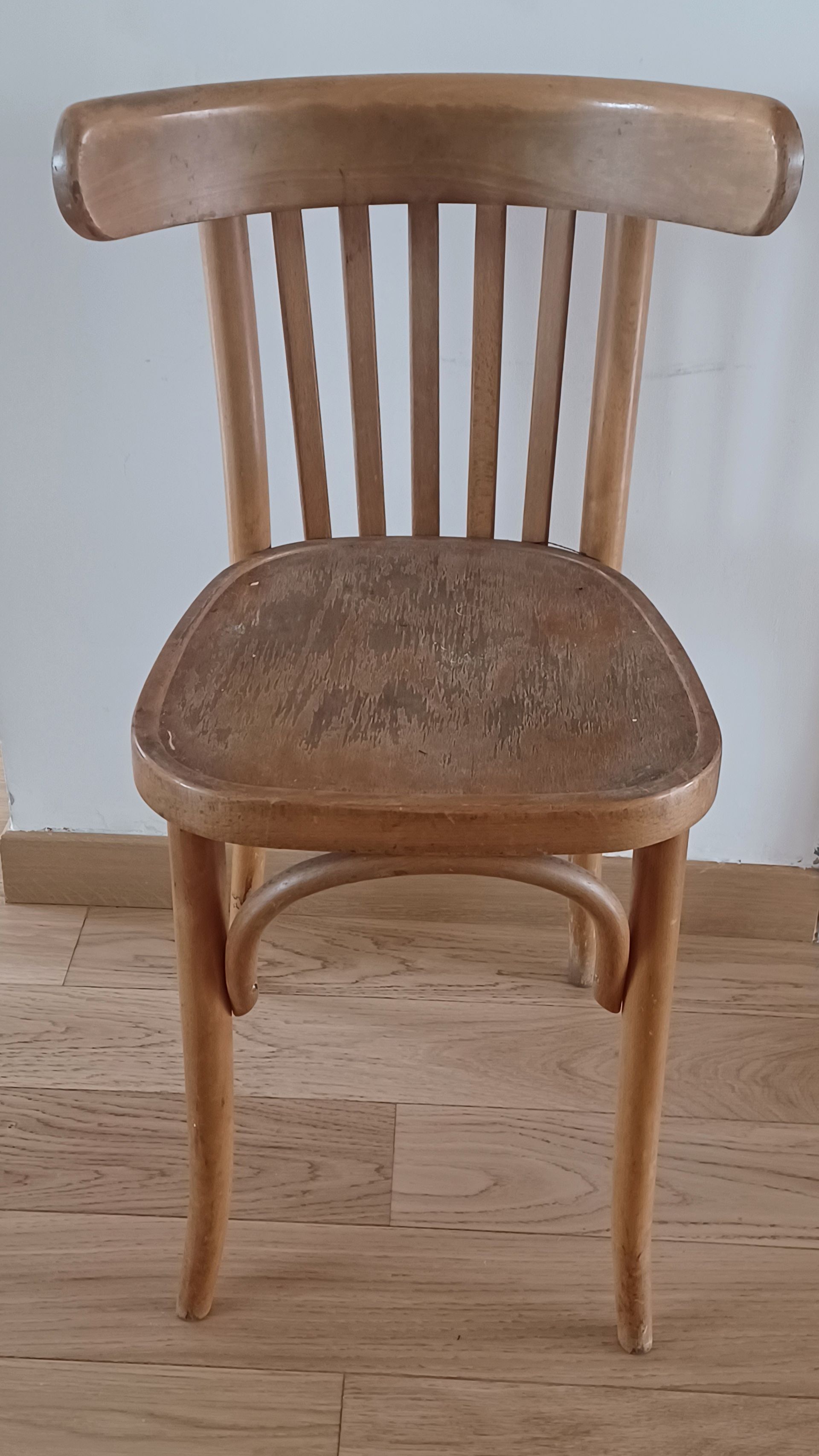 Chaise en bois avec dossier incurvé et assise tressée sur un parquet clair