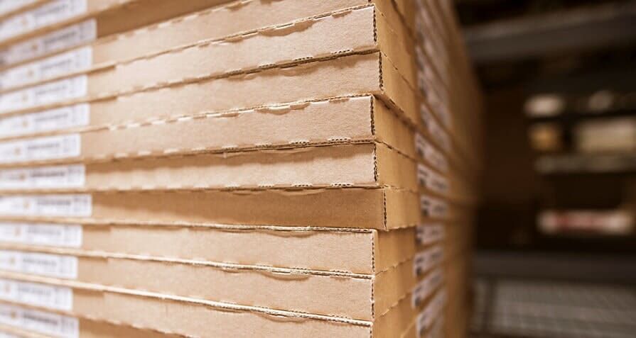 Pilha de caixas de papelão em uma prateleira de armazém.