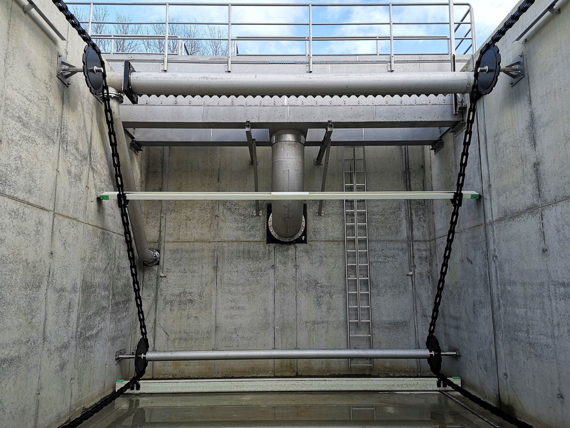 Ein großes Metallrohr hängt an einer Betonwand