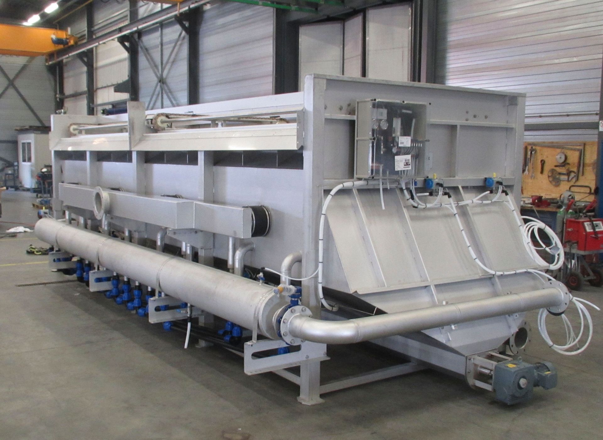 In einer Lagerhalle steht eine große Maschine aus Edelstahl.