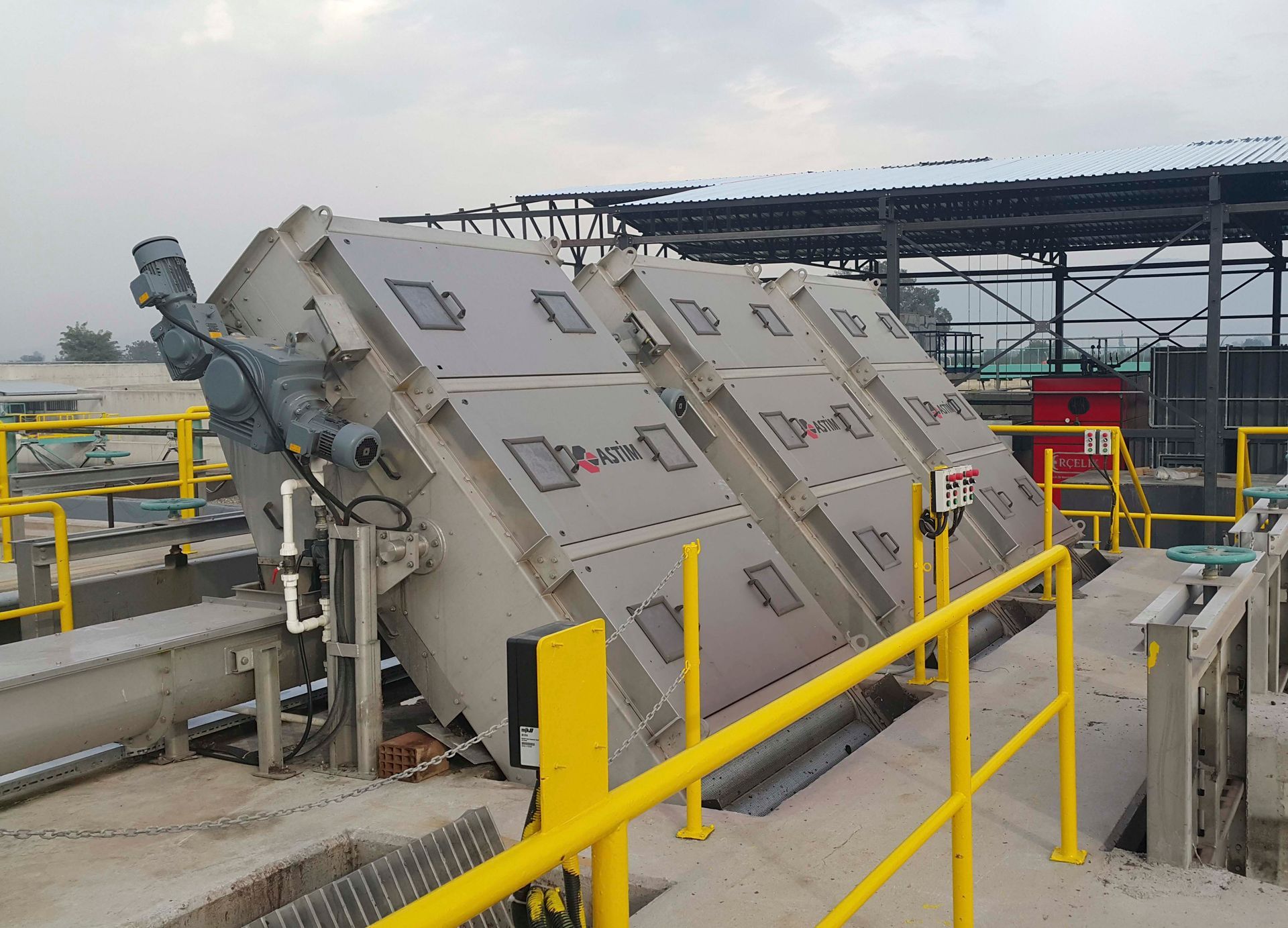 Eine große Maschine steht auf einer Betonplattform mit einem gelben Geländer.
