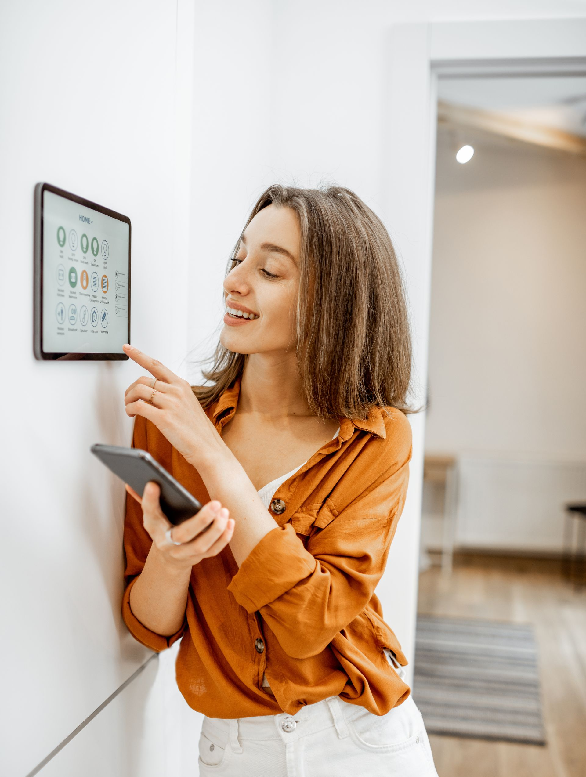 Une dame tenant une tablette devant un écran Home Touch