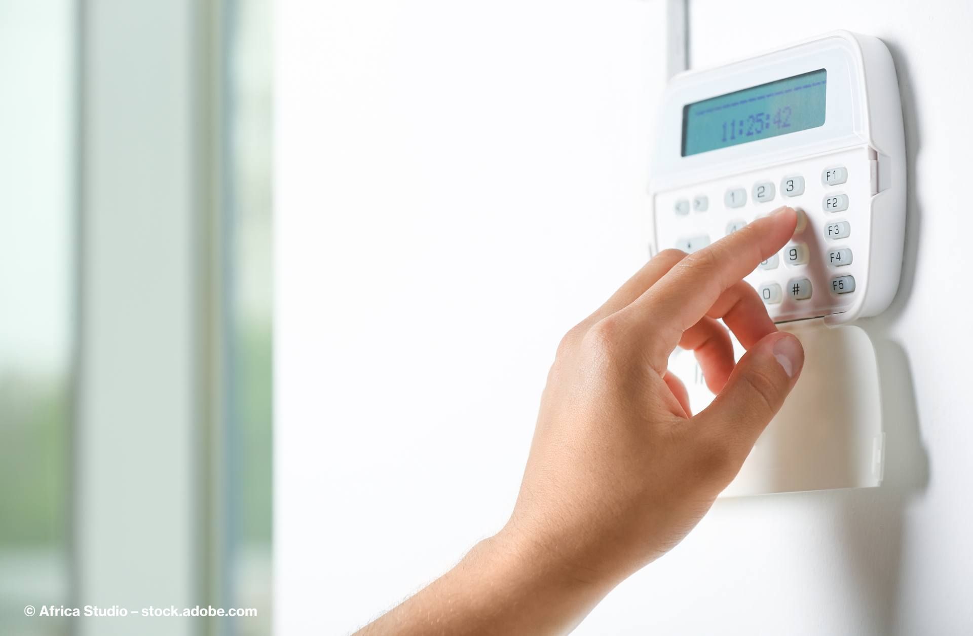 Hand drückt den Code einer Hausalarmanlage