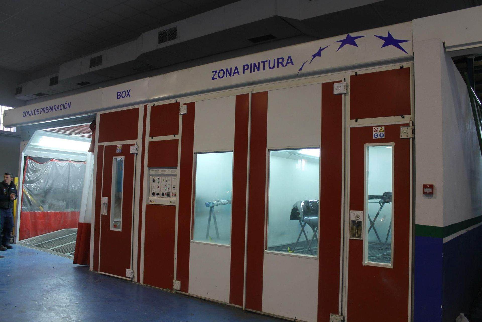 Cabina de pintura con franjas blancas y rojas, ventanas y letrero de 