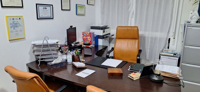 Escritorio de oficina con silla de cuero, papeles y una impresora.