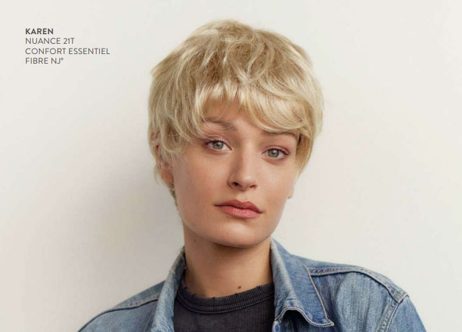 Une femme avec des cheveux courts blonds, un t-shirt bleu et une veste en jeans