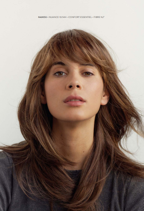 Une femme avec des cheveux bruns longs et un chemisier noir