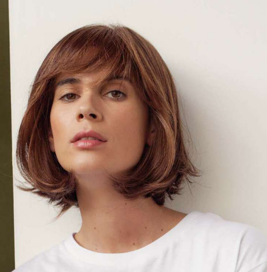 Une femme avec des cheveux bruns mi-longs et un t-shirt blanc