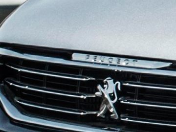 Primer plano de una parrilla plateada de Peugeot y el emblema del león en la parte delantera de un coche.