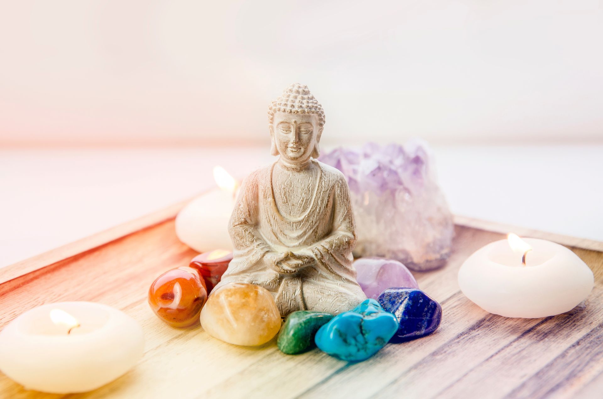 Un petit bouddha entouré de pierres et de bougies