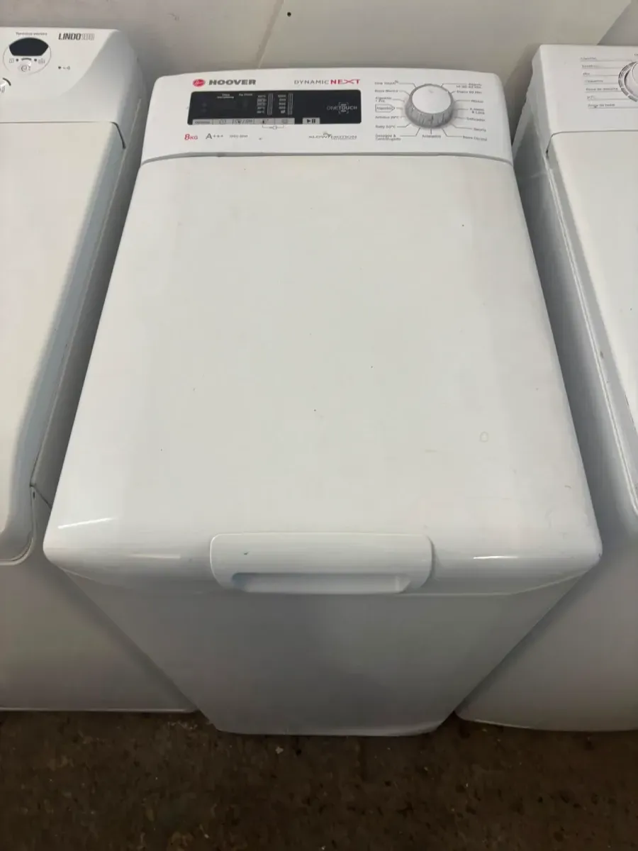 Lavadora blanca de carga superior entre dos electrodomésticos en un área de lavandería.