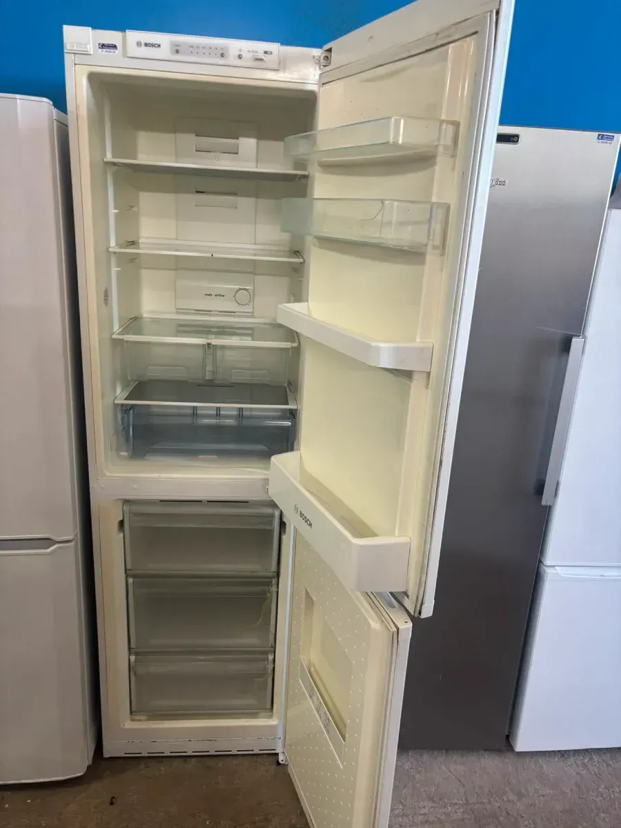 Refrigerador blanco abierto con estantes y cajones vacíos en el escaparate de una tienda.
