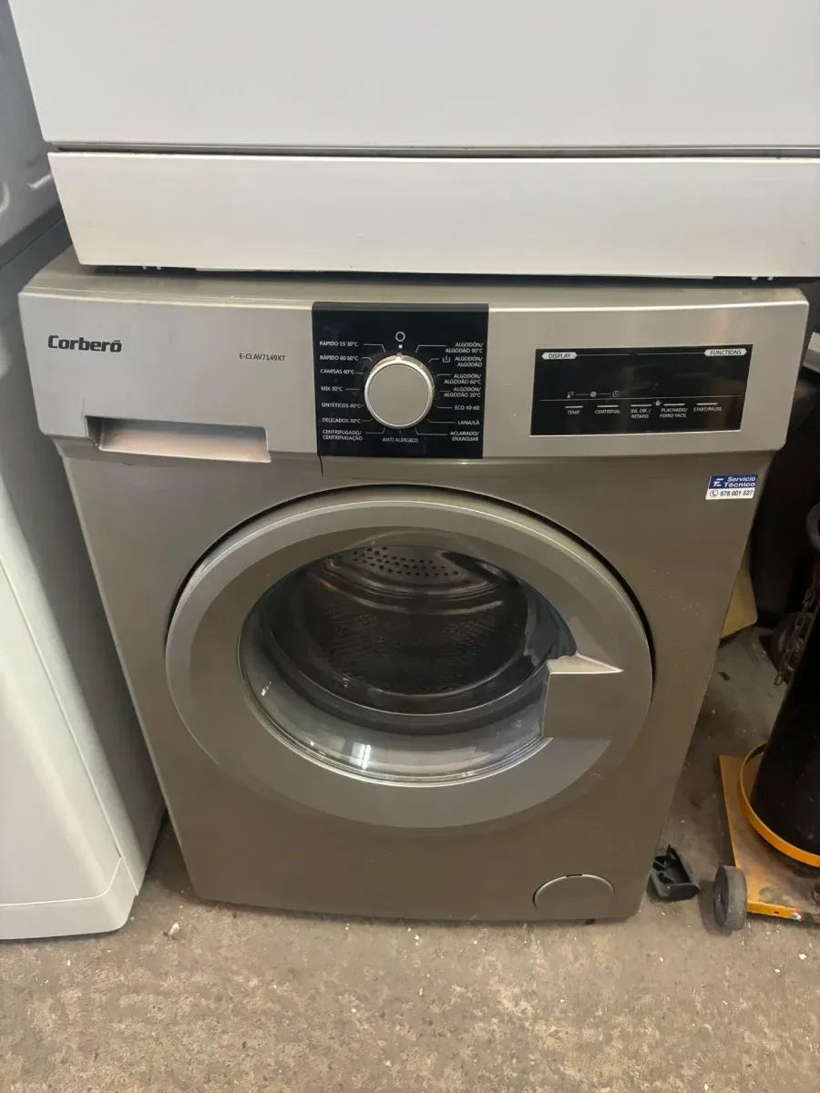 Lavadora de carga frontal con puerta y panel de control grises en una zona de lavandería