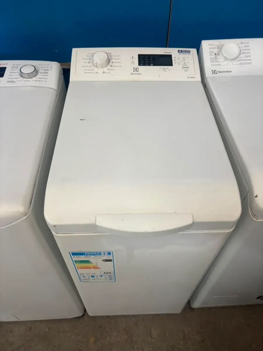 Lavadora blanca de carga superior en una fila de electrodomésticos en una tienda o sala de exposición de lavandería.