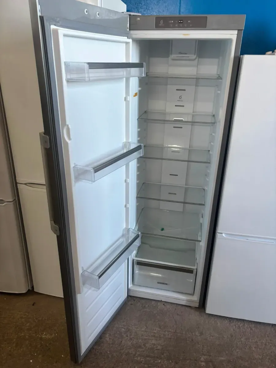 Refrigerador abierto con estantes y cajones del congelador vacíos en una cocina.