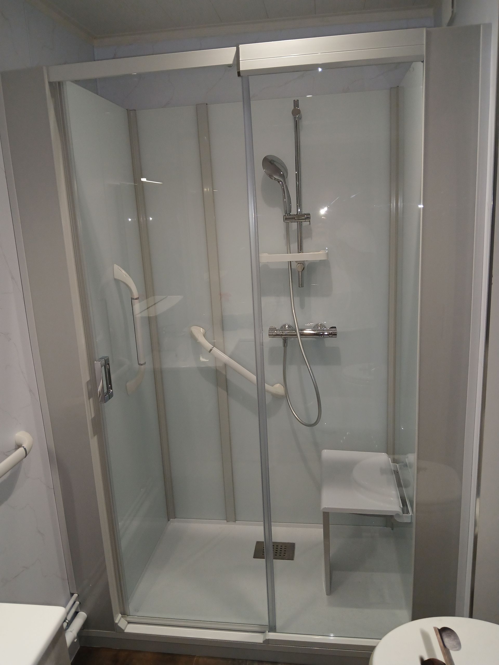 Main tenant une barre d'appui argentée près d'un lavabo.