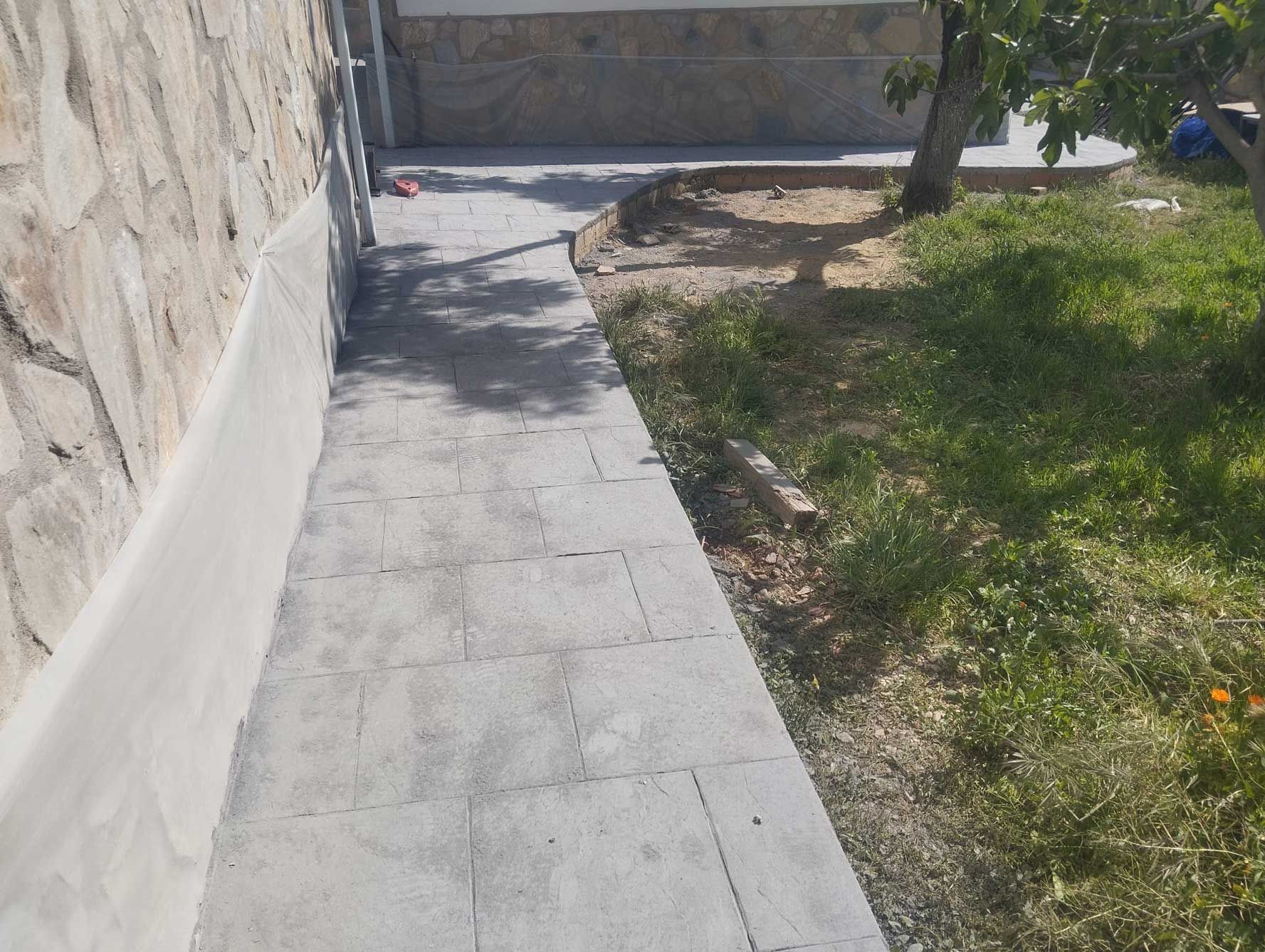 Un camino de piedra que conduce a una zona de césped junto a un muro de piedra.