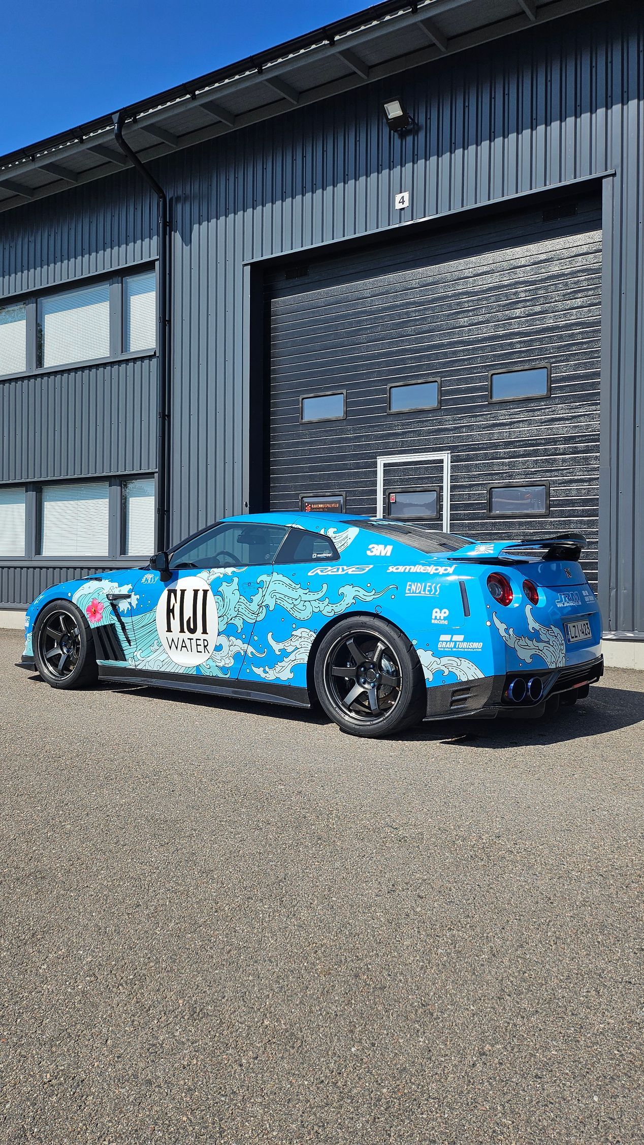 Valkoinen BMW X6 mustilla yksityiskohdilla pysäköitynä autotalliin.