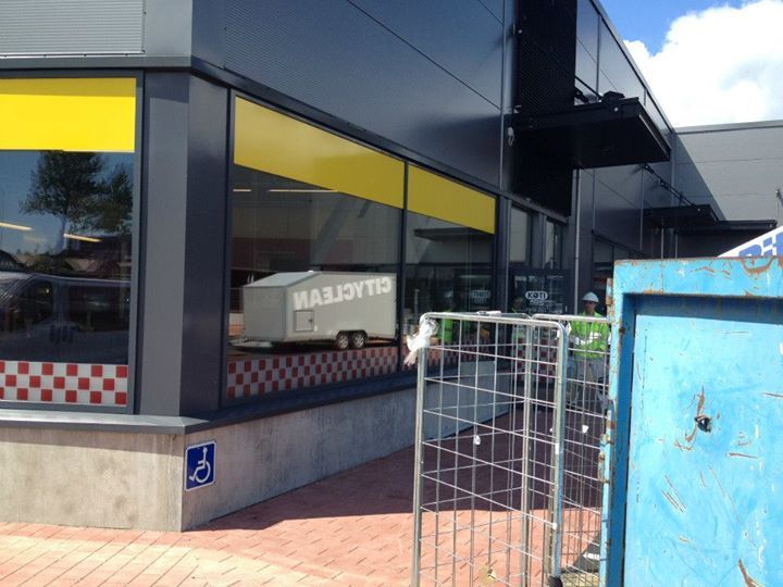 Rakennuksen ulkopinta, jossa on esteettömyyskyltti. Ikkunassa näkyy Cityclean-perävaunu.