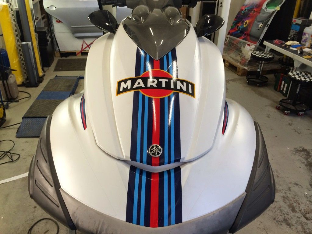 Lähikuva valkoharmaasta vesiskootterista, jossa on Martini-kilparaidat.