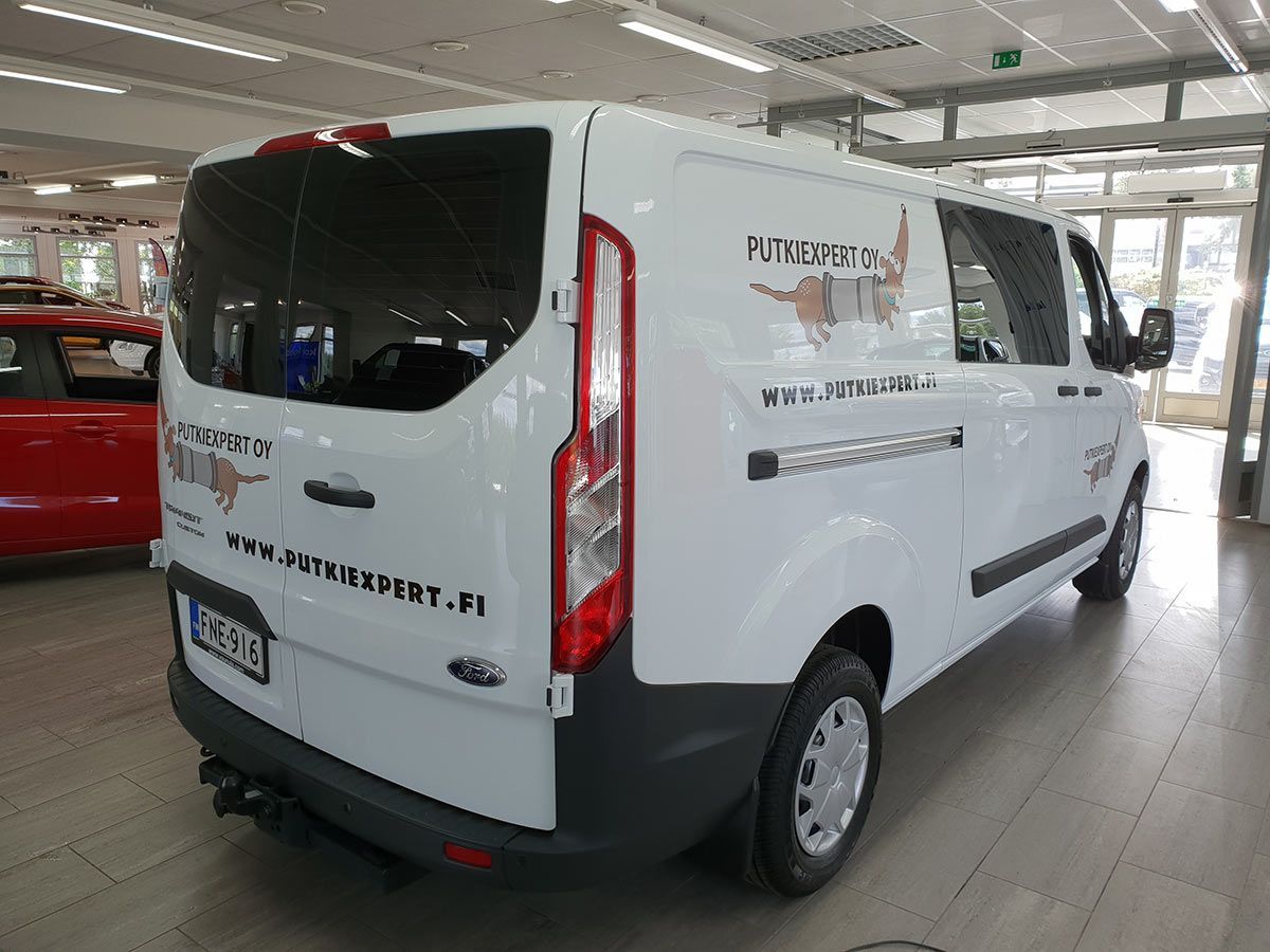 Valkoinen Ford Transit -pakettiauto näyttelytilassa, brändättynä.