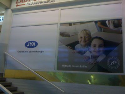 JYA-huonekaluliikkeen kyltti, jossa lapset leikkivät laatikossa.