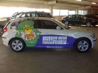 Valkoinen auto, jossa on vihreä hirviöaiheinen grafiikka, teksti 