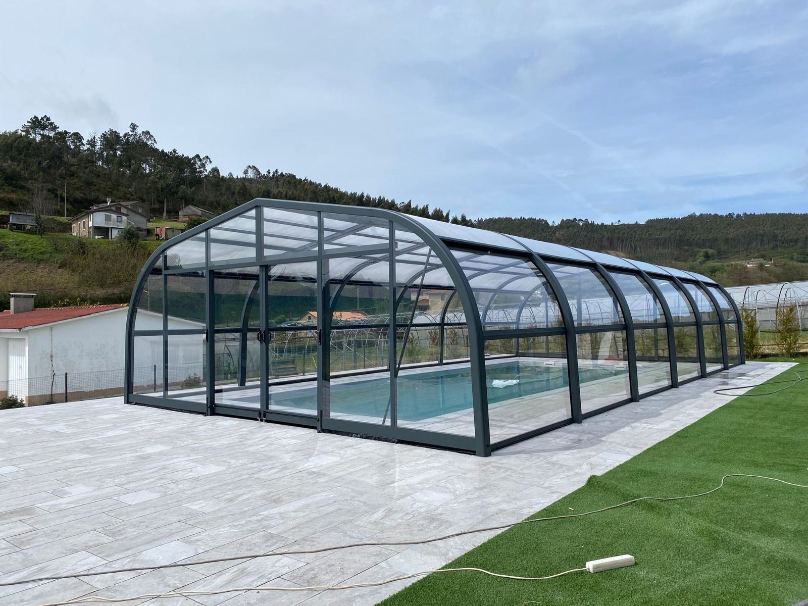 Una gran piscina está cubierta por un gran cerramiento de cristal.